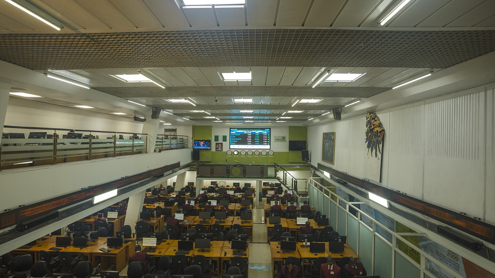 An empty stock-exchange trading floor with rows of desks and electronic market boards
