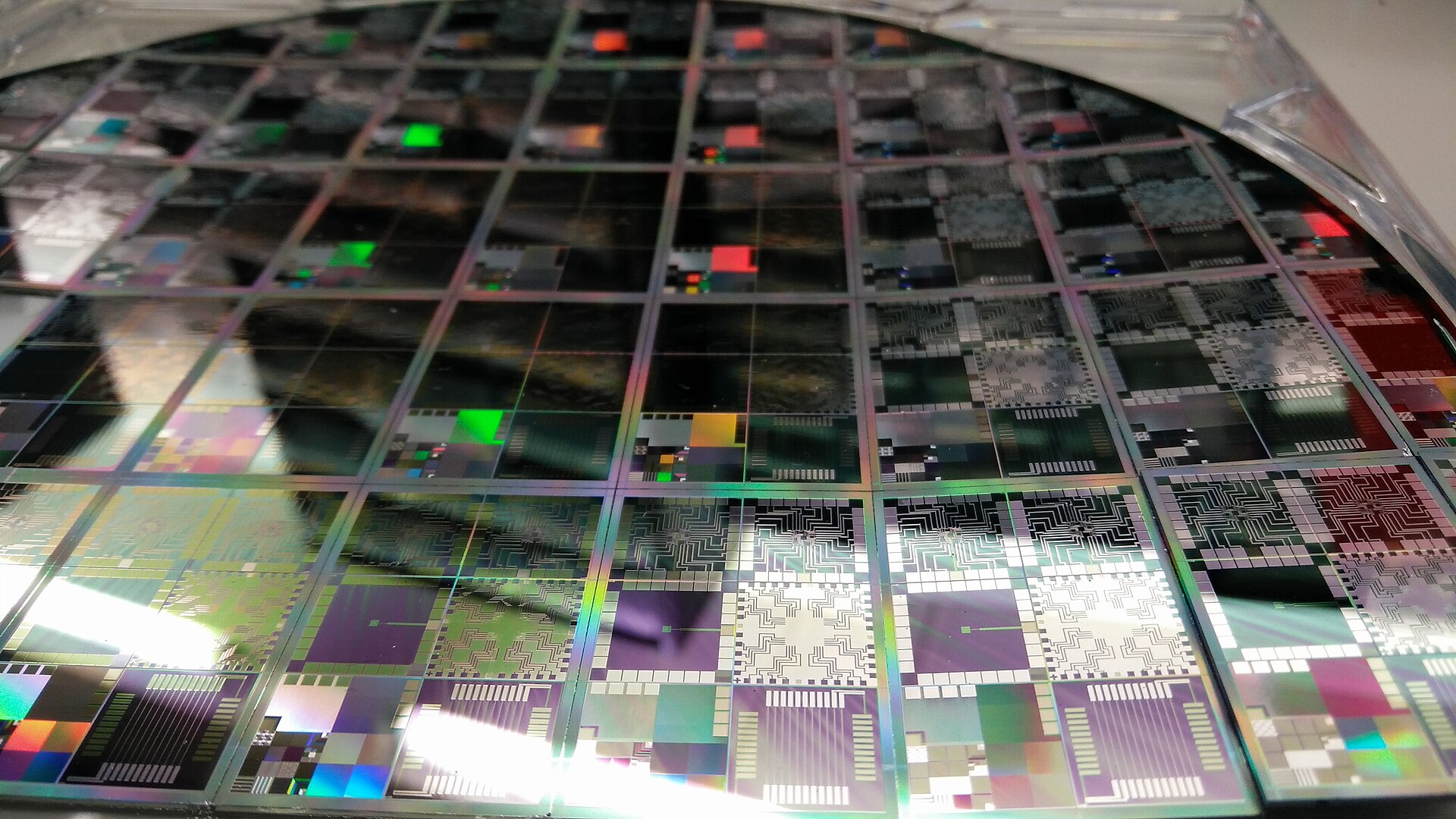 Close-up photograph of a microelectronics semiconductor wafer with patterned test chips.