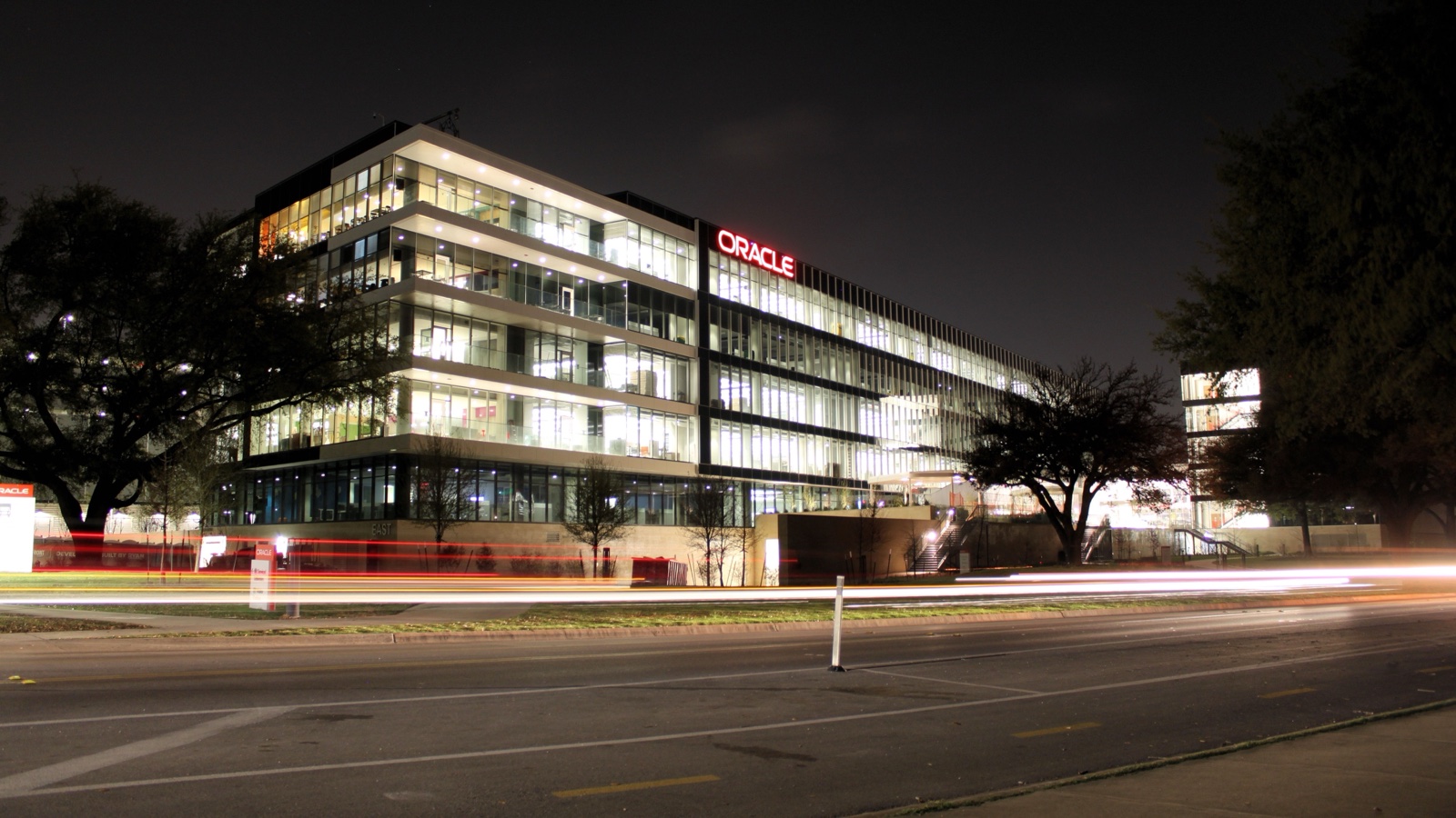 Night photograph of Oracle Riverside Campus in Austin, with illuminated offices and traffic light trails