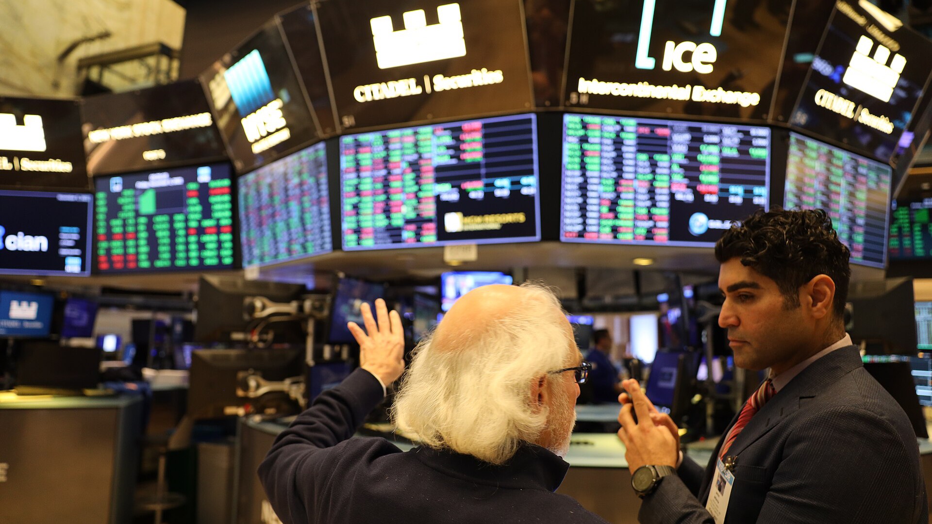 Two people discuss market data on the New York Stock Exchange trading floor