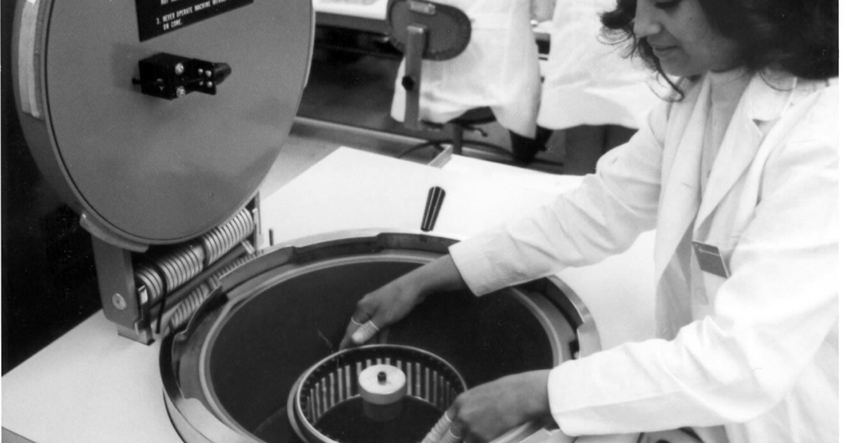 Une technicienne de fabrication d'Intel utilise un équipement de détection de fuites pour semi-conducteurs dans une photographie historique d'usine.