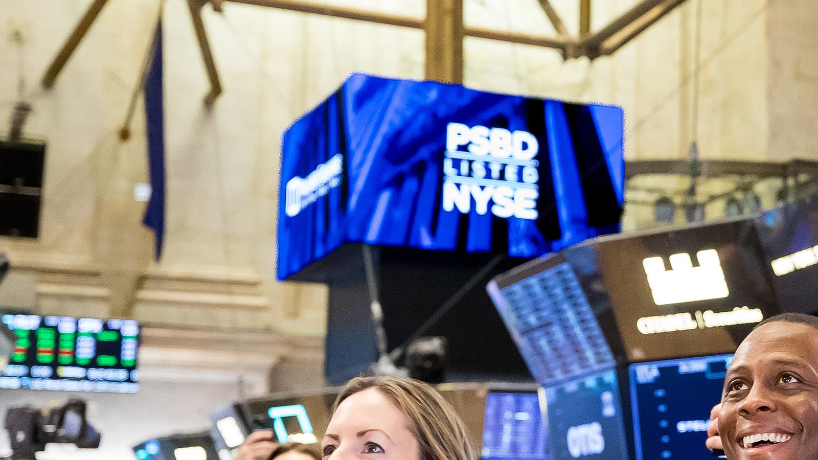People applaud beneath NYSE screens on the New York Stock Exchange trading floor