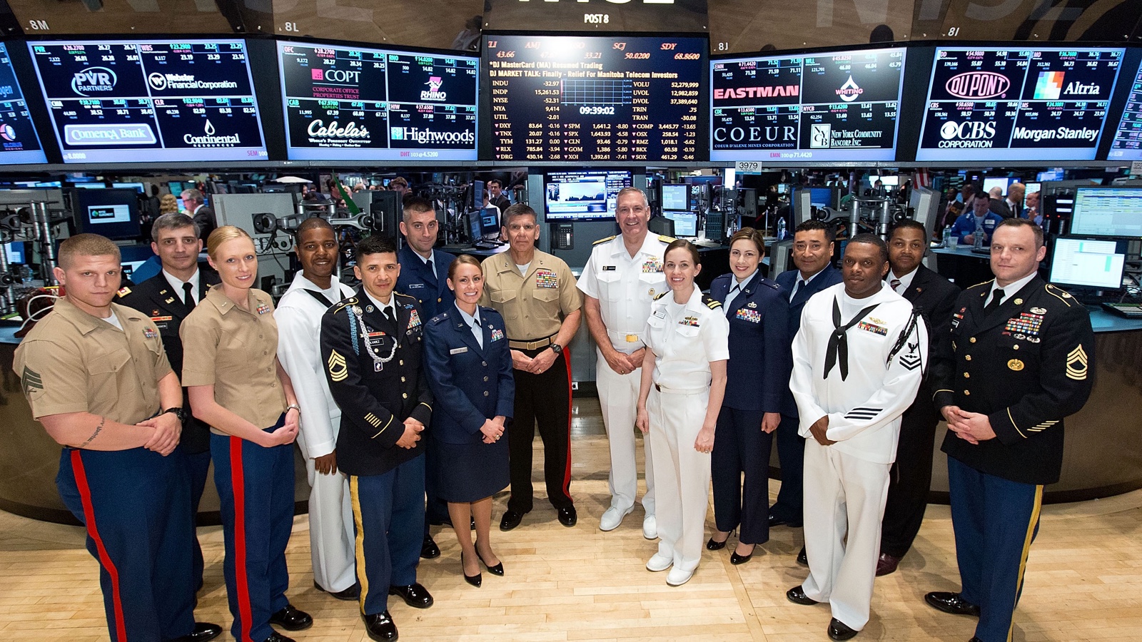 U.S. service members stand beneath market screens on the New York Stock Exchange trading floor