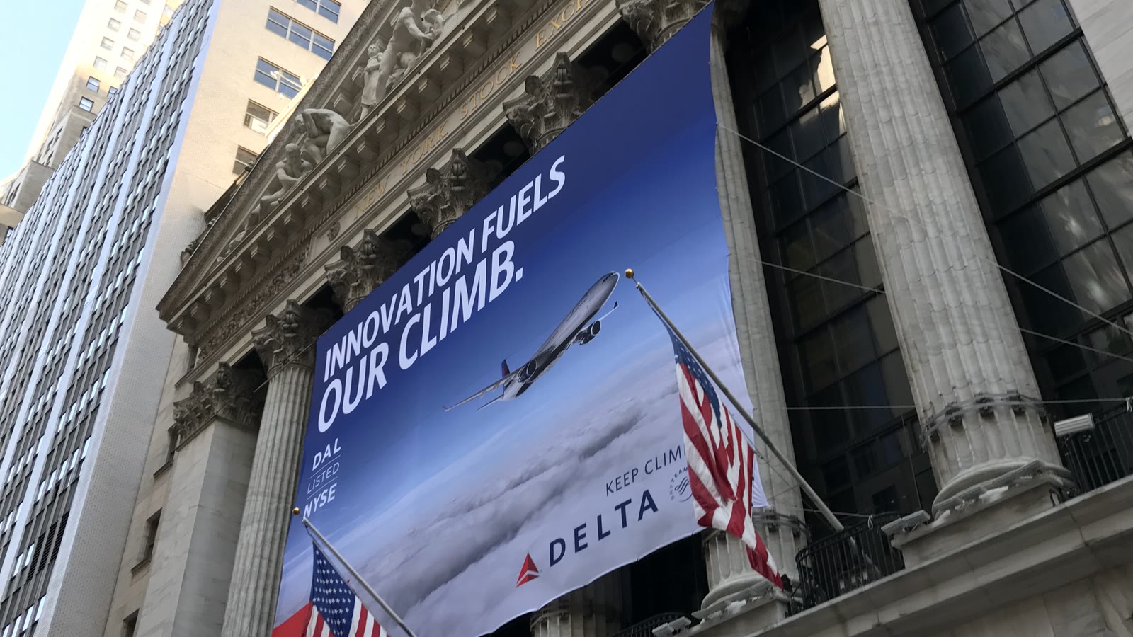 Façade de la Bourse de New York avec colonnes, drapeaux américains et bannière d’introduction de Delta