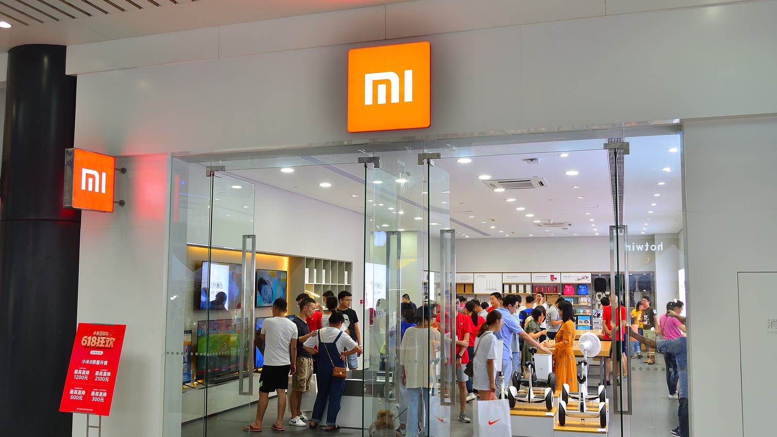Visitors gather around smartphone displays inside a brightly lit Xiaomi store in Hangzhou