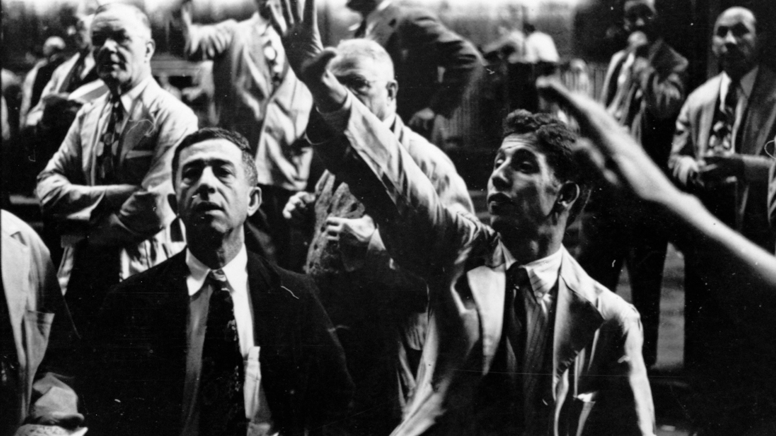 Three Chicago Board of Trade traders gesture during a crowded 1949 trading session in a black-and-white photograph