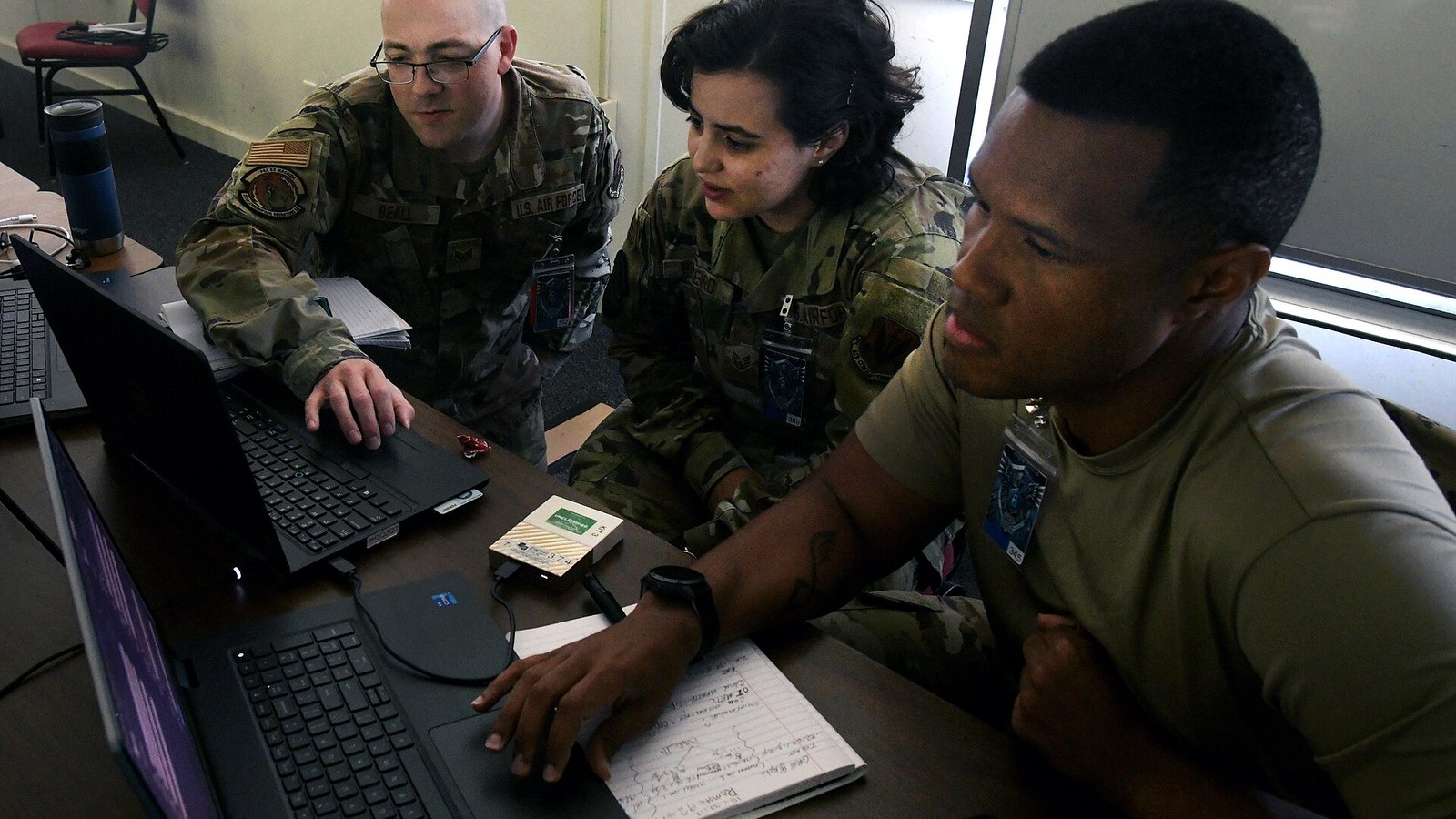 Three military cyber operators monitor computer screens during a network-security exercise