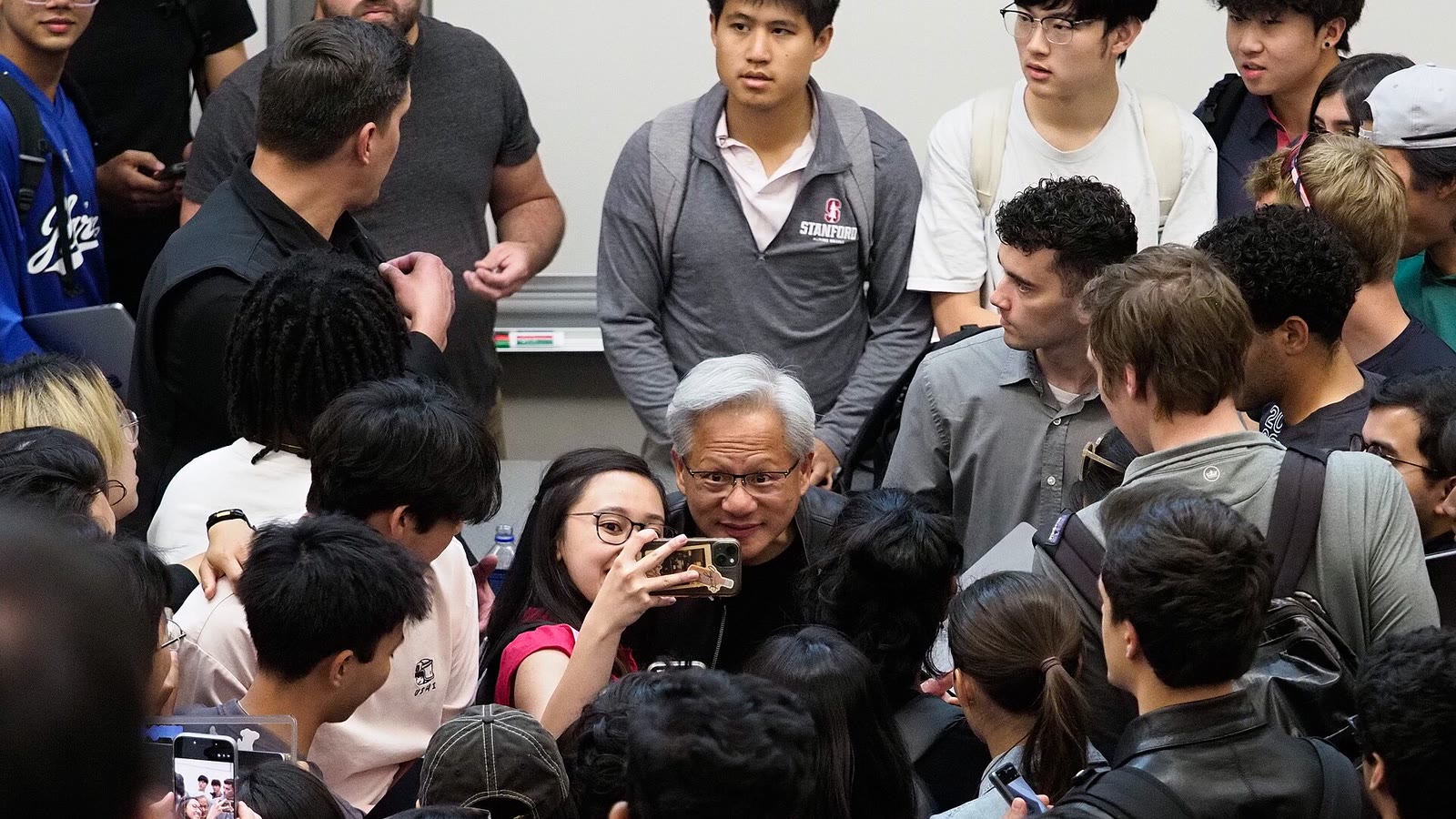 NVIDIA CEO Jensen Huang surrounded by Stanford students after a course talk