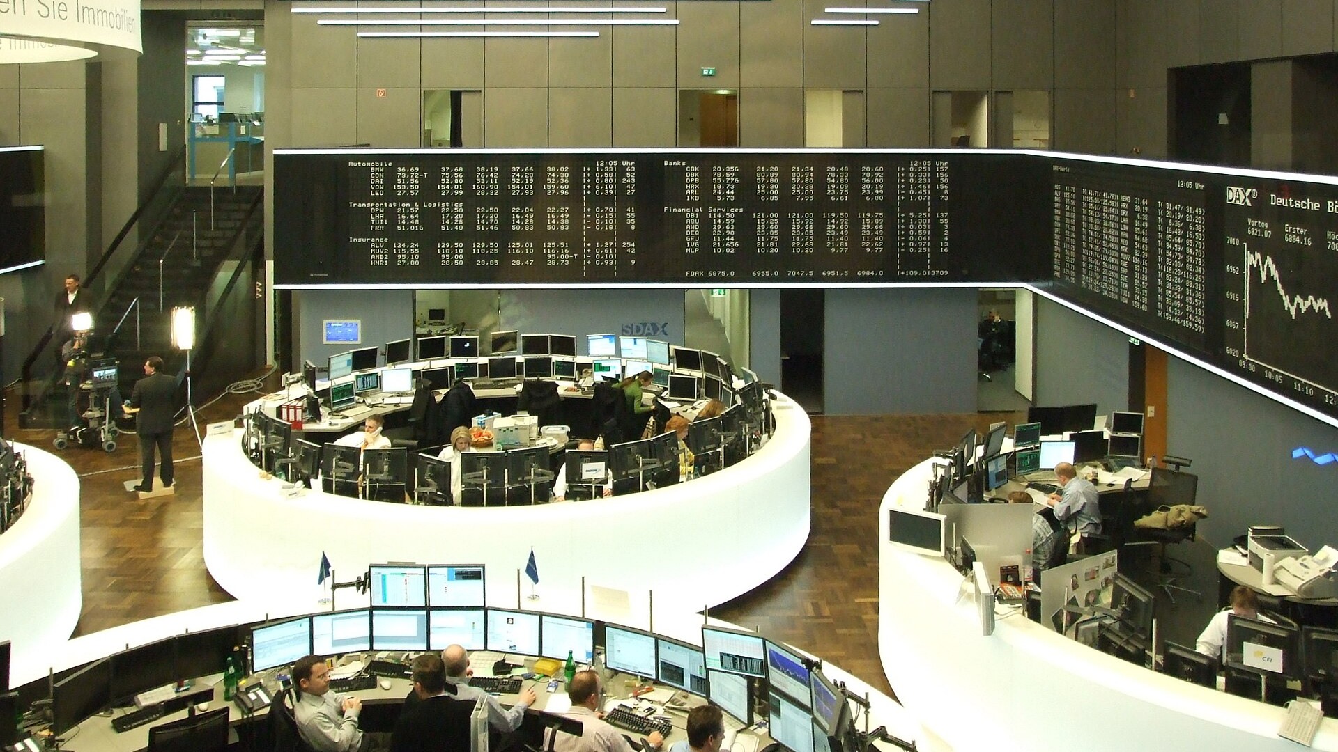 Traders work at circular desks beneath market boards on the Frankfurt Stock Exchange floor