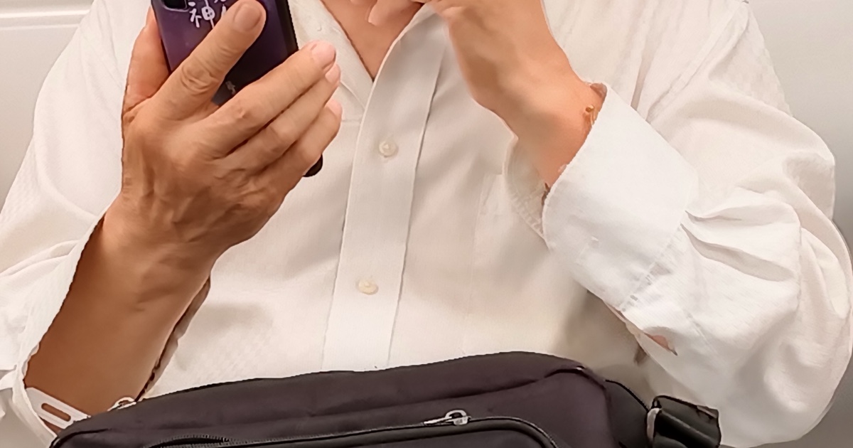 Une personne en chemise blanche tient un téléphone intelligent, illustrant les vérifications d’identité mobiles sécurisées.