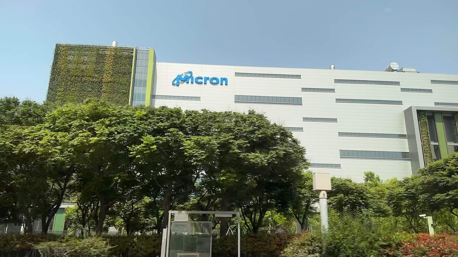 Micron's memory chip fab in Taichung, Taiwan, with the Micron logo on a white facade behind green trees