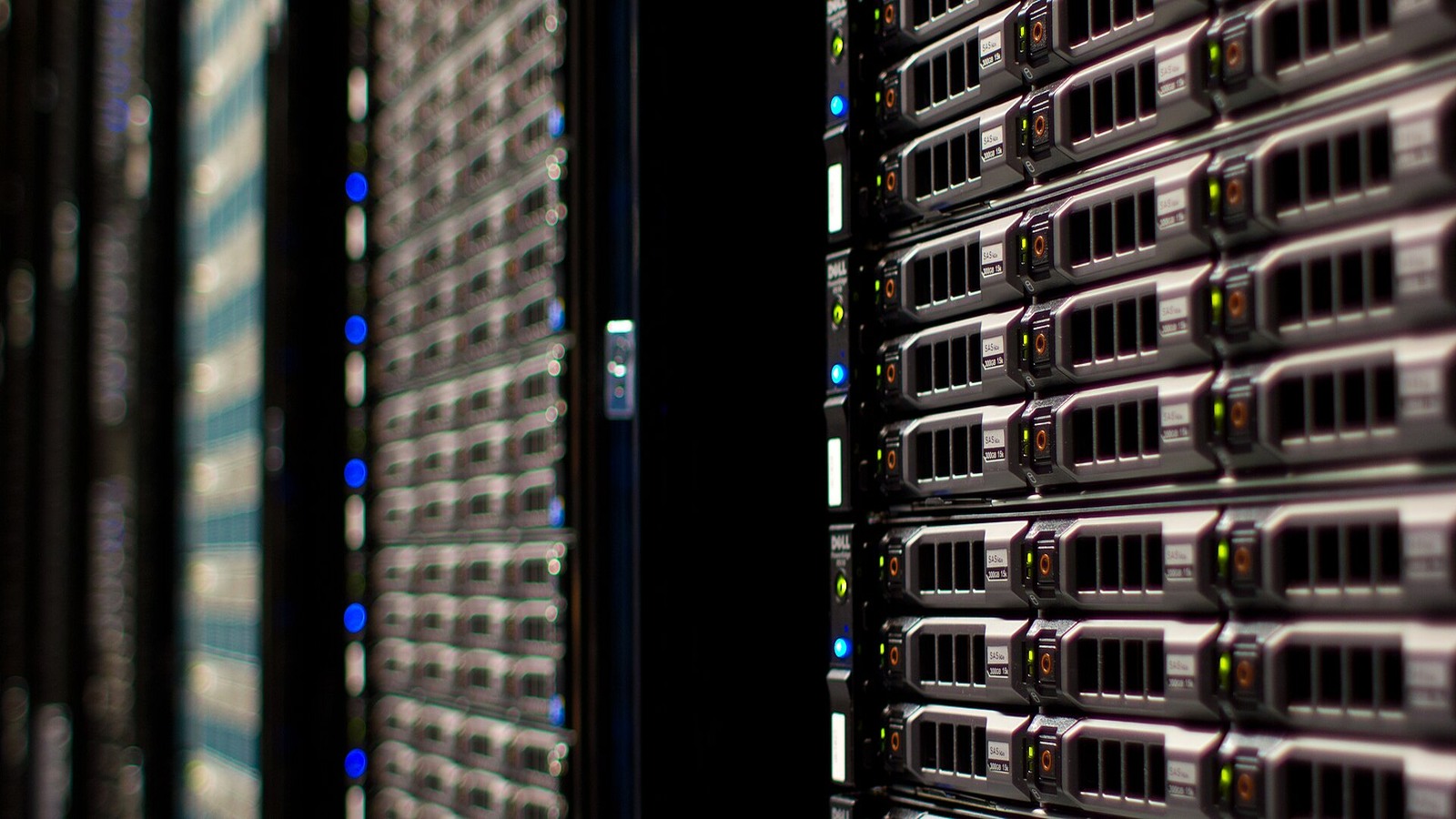 Close view down an aisle between occupied server racks in a data centre.