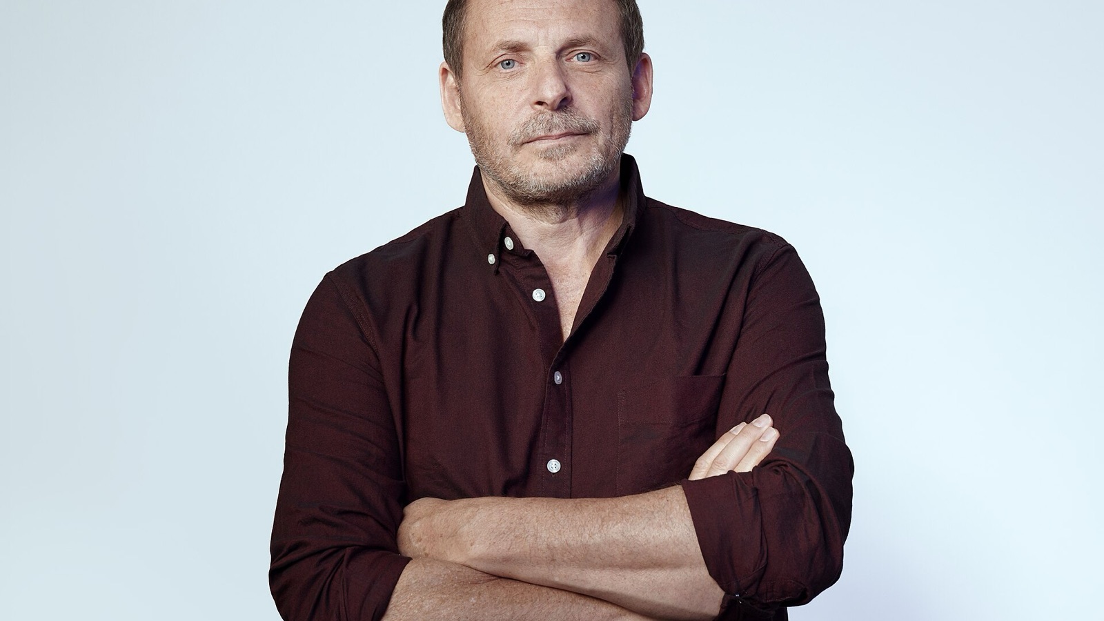 Nebius CEO Arkady Volozh in a studio portrait, arms crossed, against a pale blue backdrop