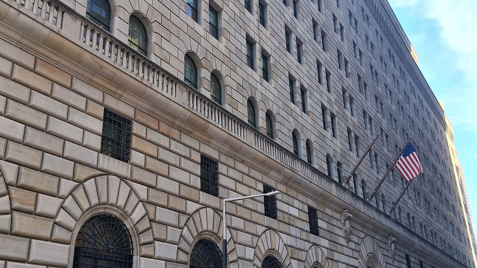 La façade en pierre de la Banque fédérale de réserve de New York, rue Liberty, avec un drapeau américain