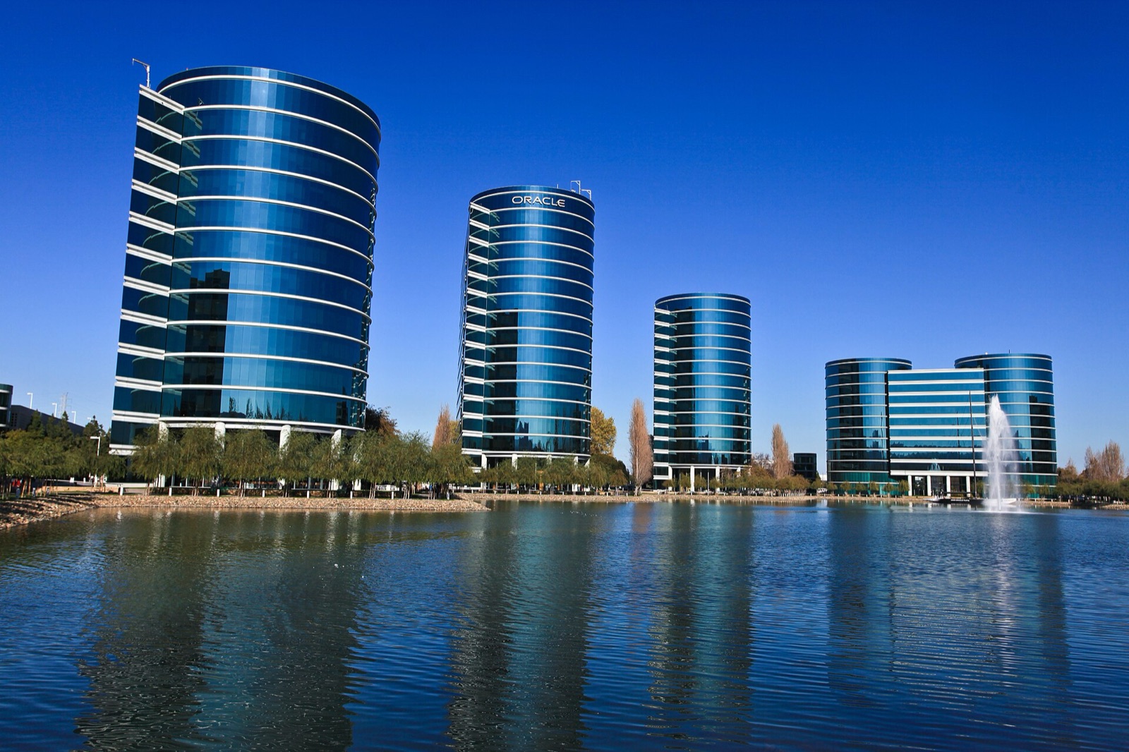 Les tours de verre du siège d'Oracle à Redwood Shores, en Californie, se reflétant dans un lagon sous un ciel bleu