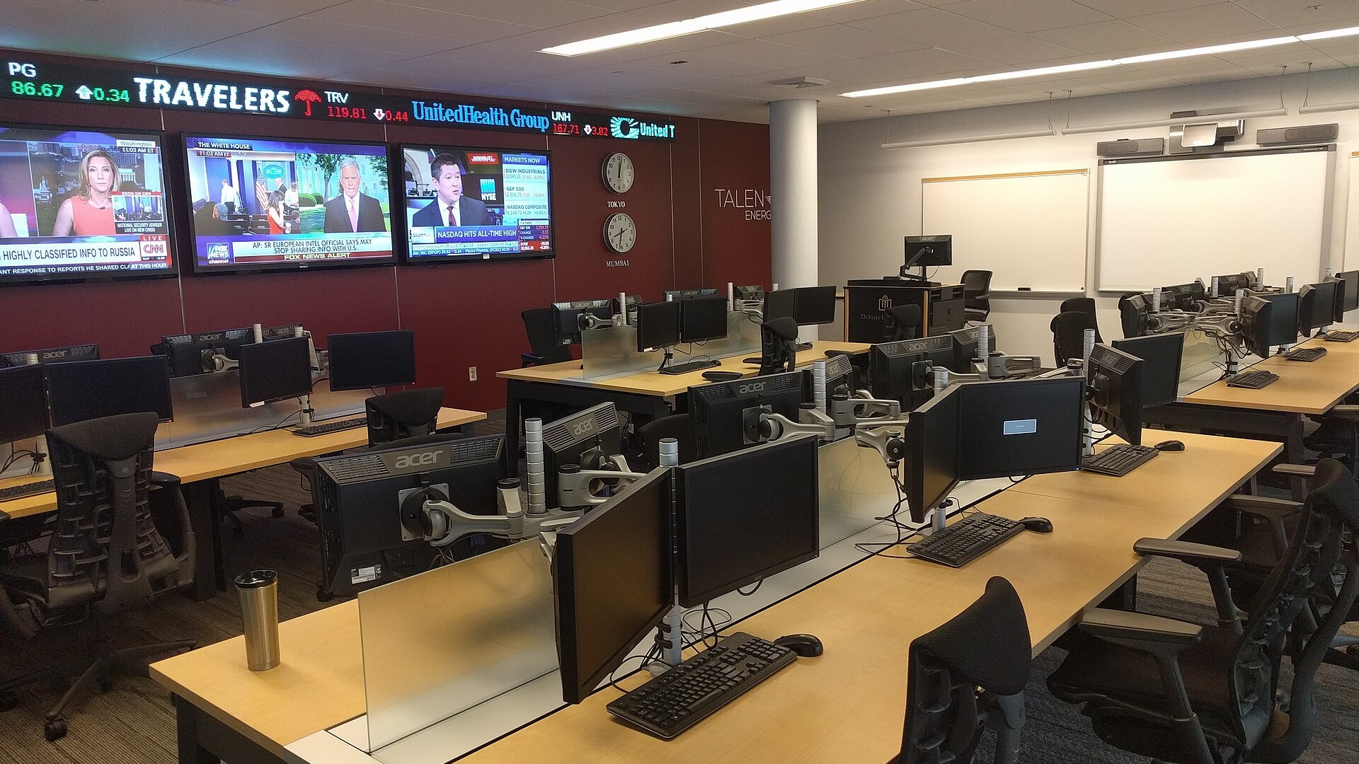 An empty university financial trading room with rows of monitors, market screens and a wall stock ticker