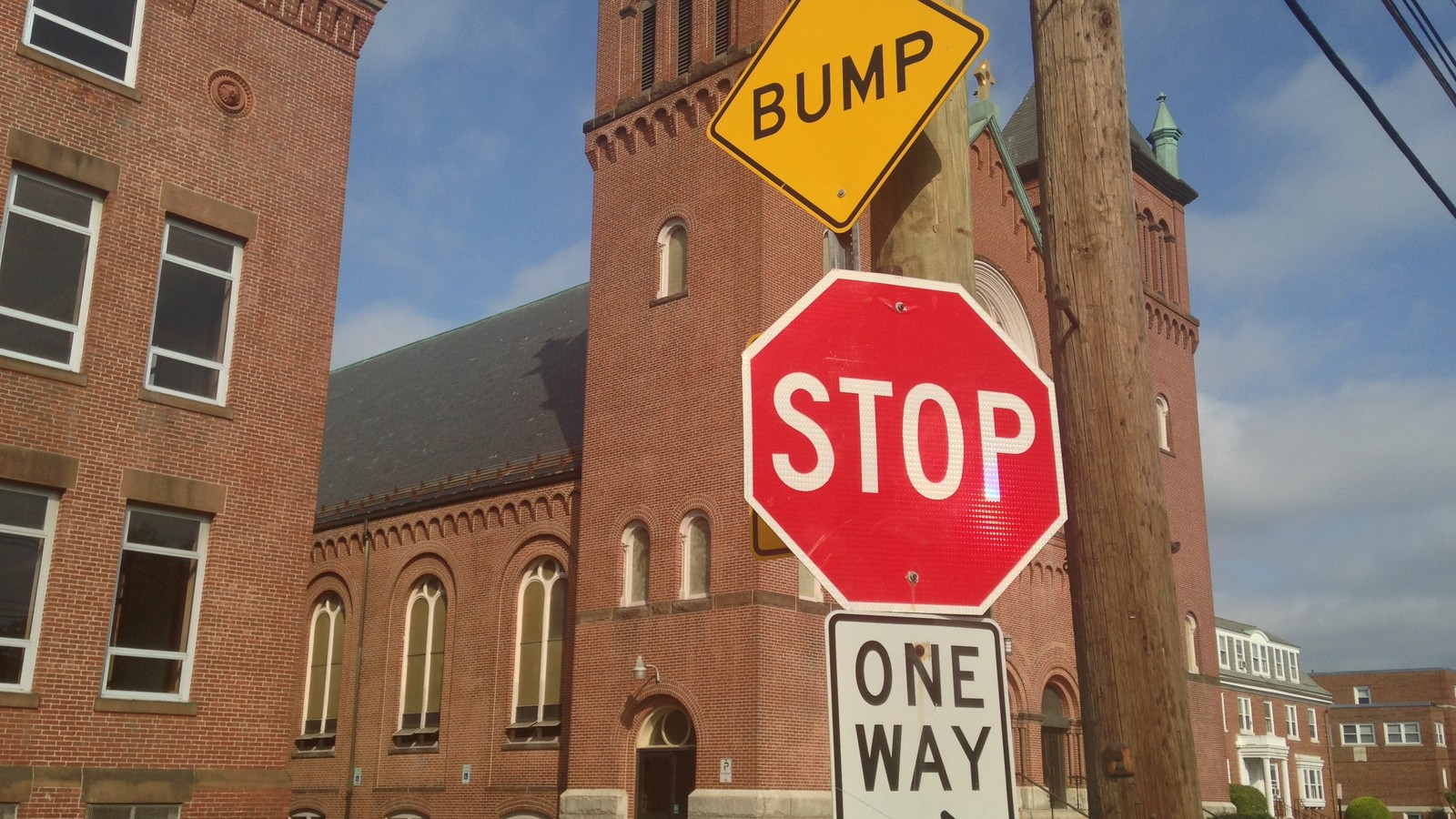 A red STOP sign in front of brick buildings, with other road signs nearby