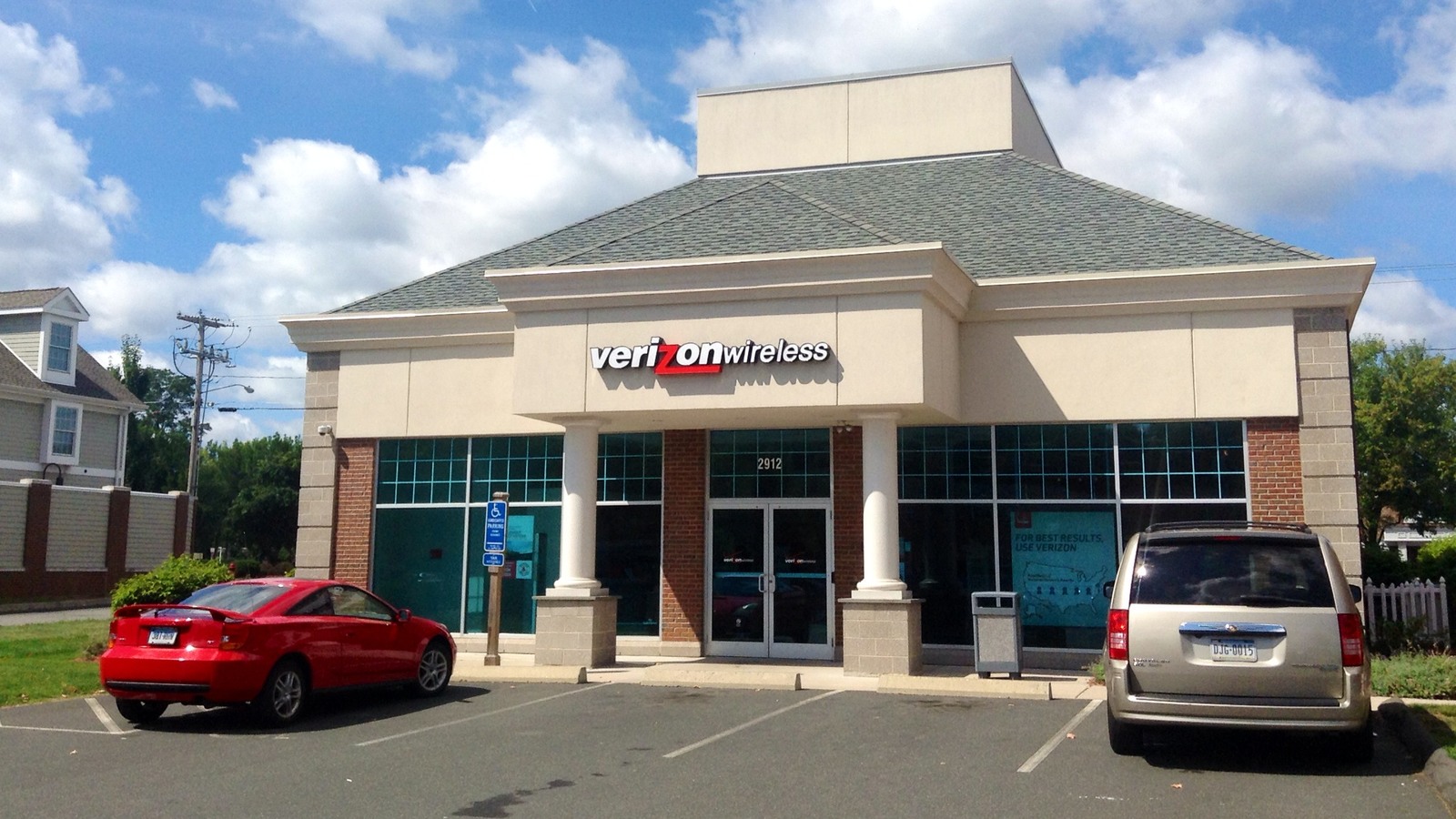 Archival photograph of a Verizon Wireless storefront, with a red car and a silver minivan parked outside.