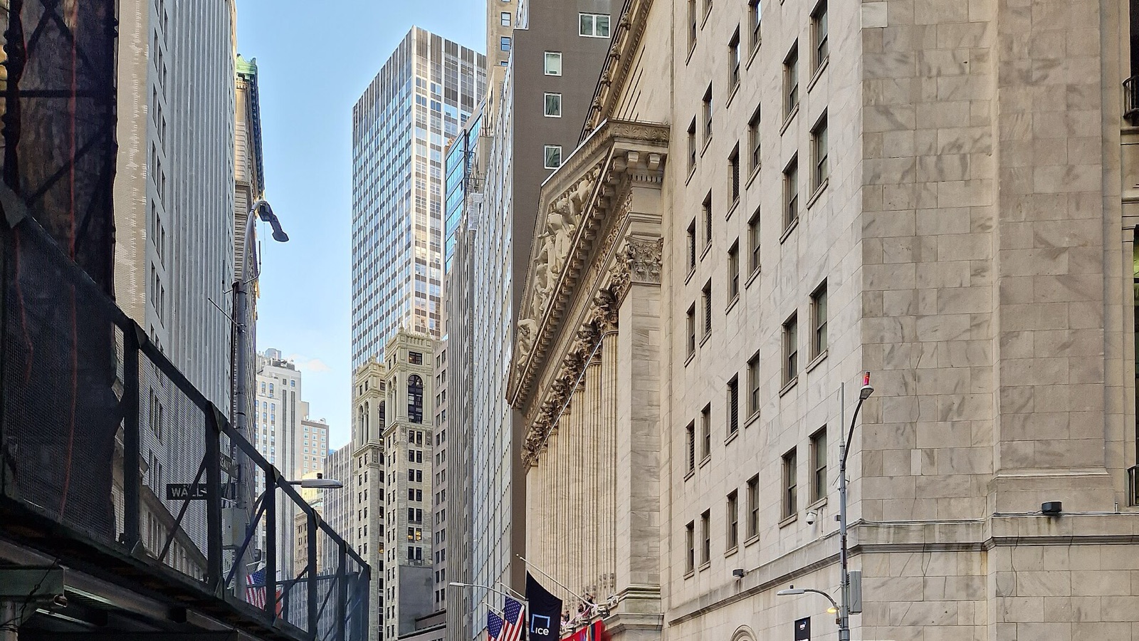 The stone exterior of the New York Stock Exchange along Wall Street, beside neighboring office buildings