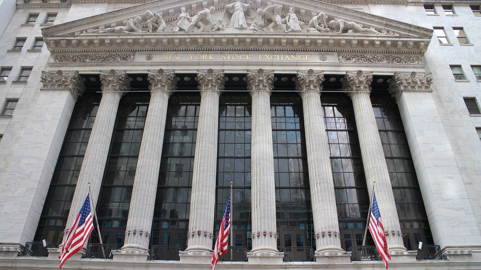 The New York Stock Exchange stone facade, columns and American flags