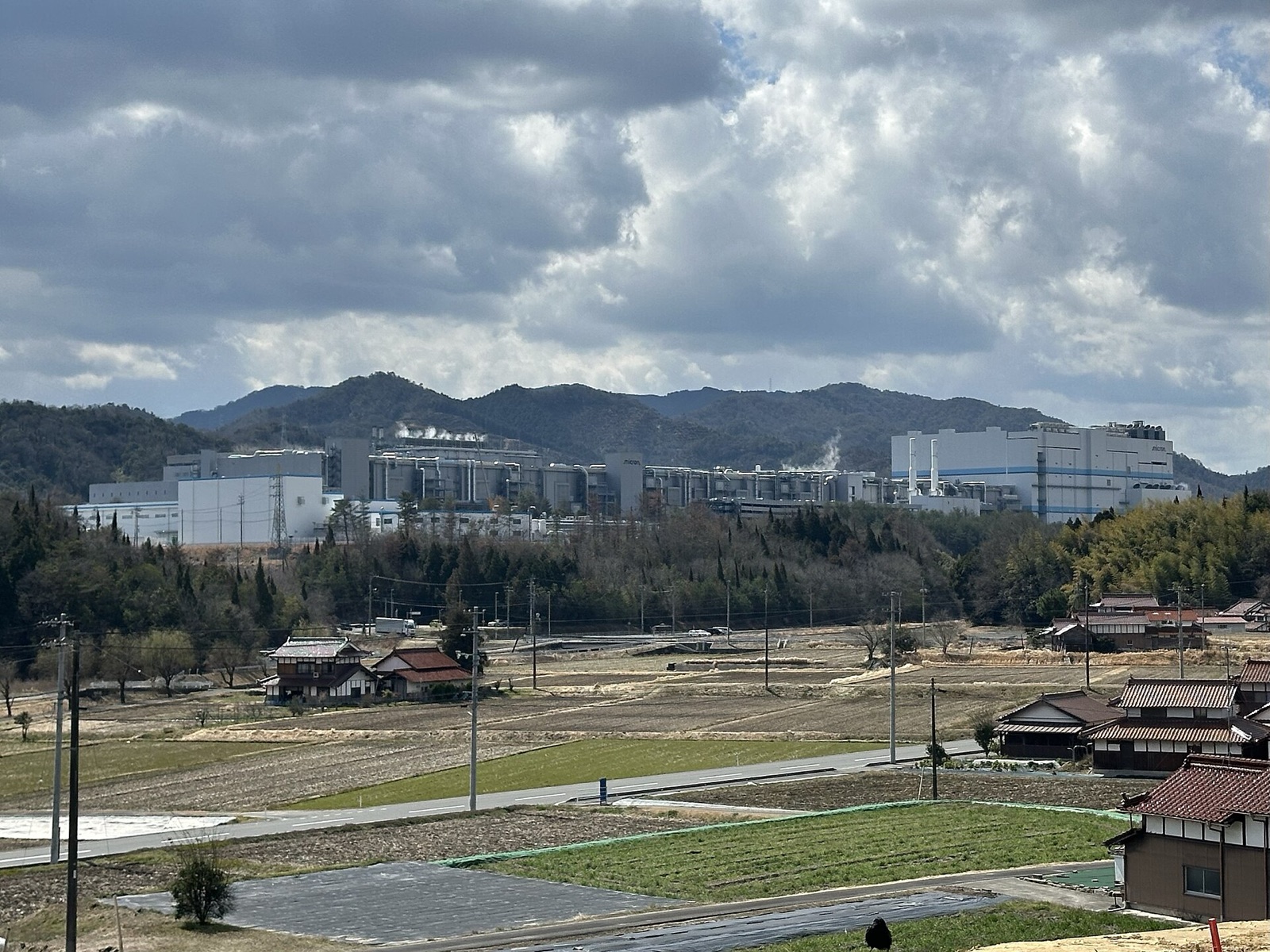 Micron’s Hiroshima memory-chip plant in Higashihiroshima, Japan, seen beyond farm fields below wooded hills