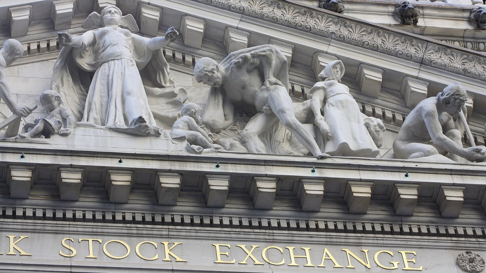 Carved stone figures and gold Stock Exchange lettering on the New York Stock Exchange facade.