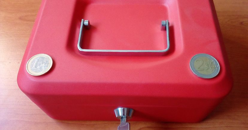 Red cash lockbox with euro coins and a key, illustrating funds reserved for option assignment