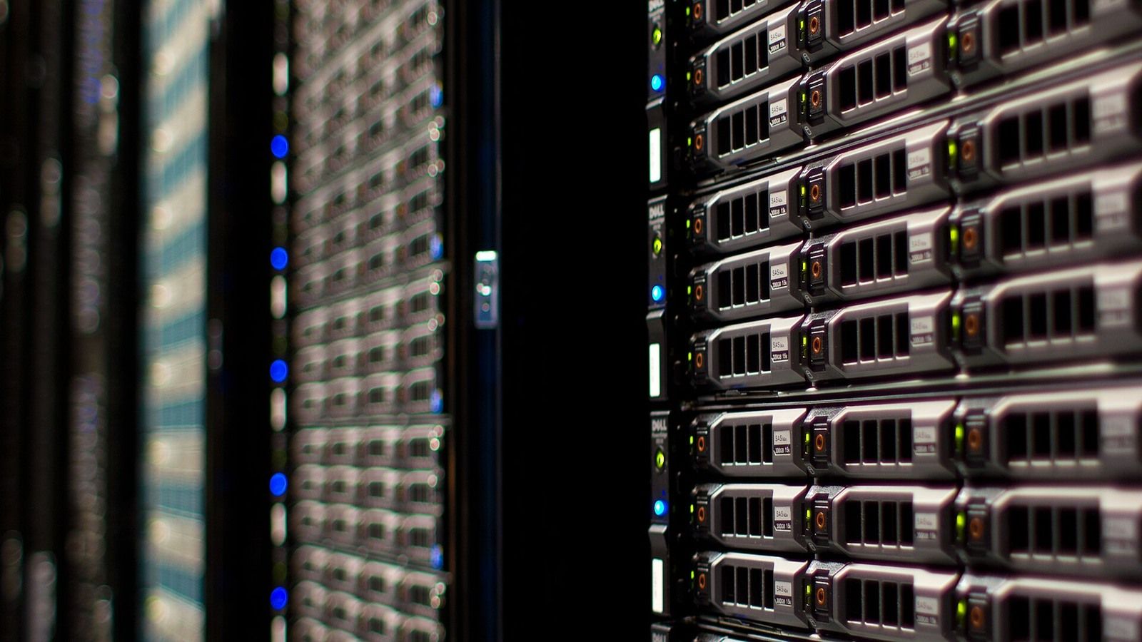 Close view down an aisle between occupied server racks in a data centre.