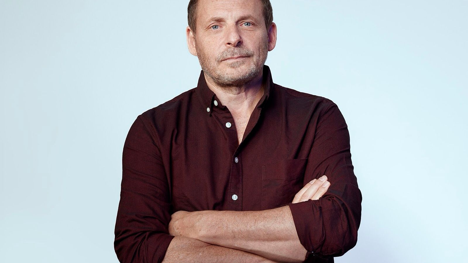 Arkady Volozh, PDG de Nebius, en portrait studio, bras croisés, sur fond bleu pâle