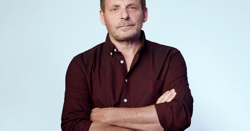 Nebius CEO Arkady Volozh in a studio portrait, arms crossed, against a pale blue backdrop