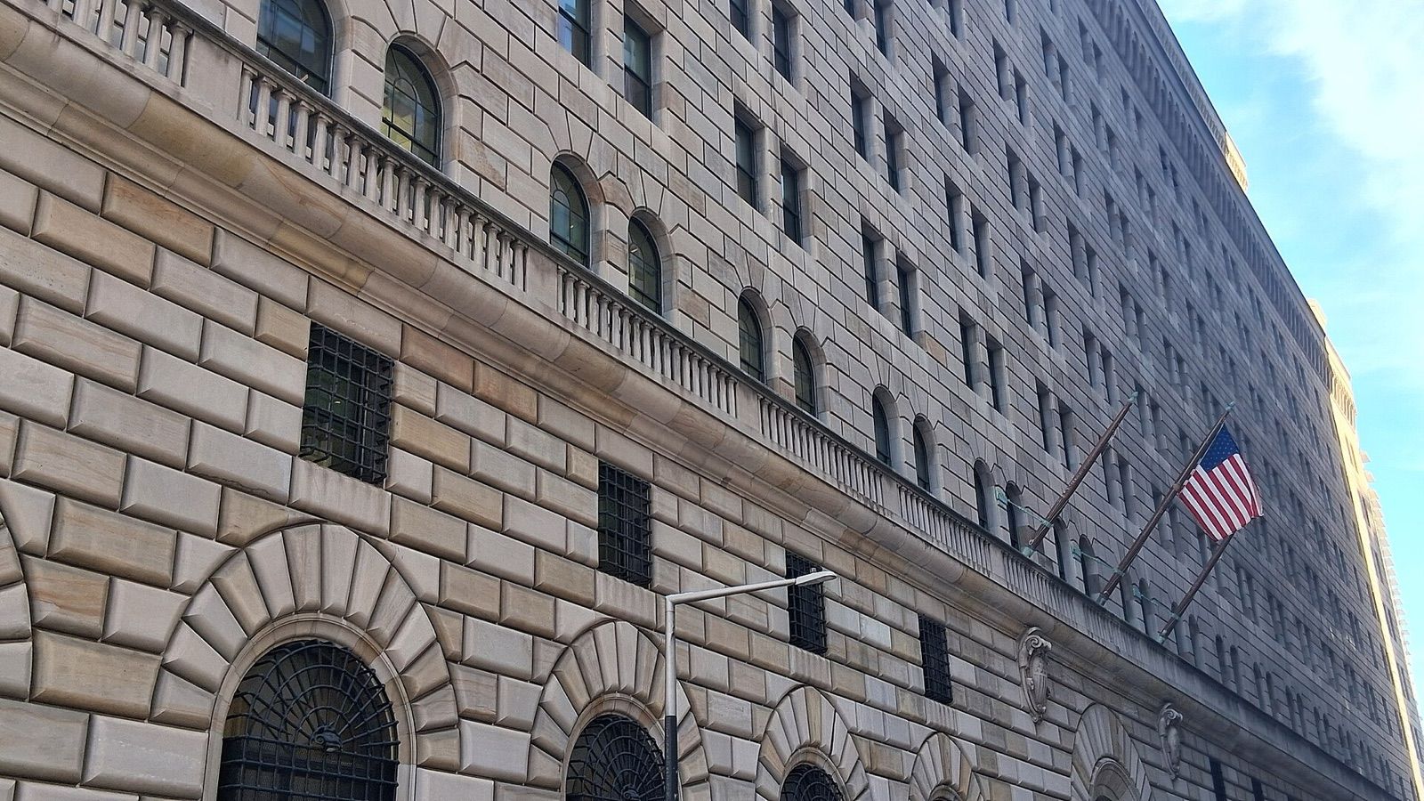 La façade en pierre de la Banque fédérale de réserve de New York, rue Liberty, avec un drapeau américain