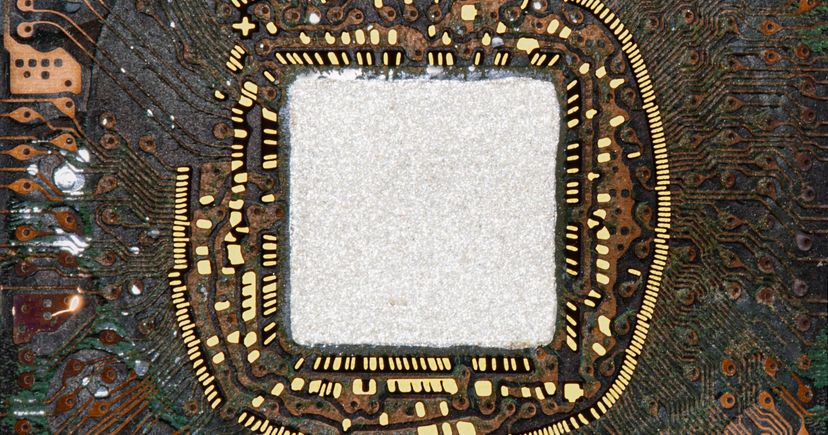 Archival macro photograph of the interior of a ball-grid-array package, with a bright square center, gold-colored contacts and circuit traces; not identified as Amkor hardware.