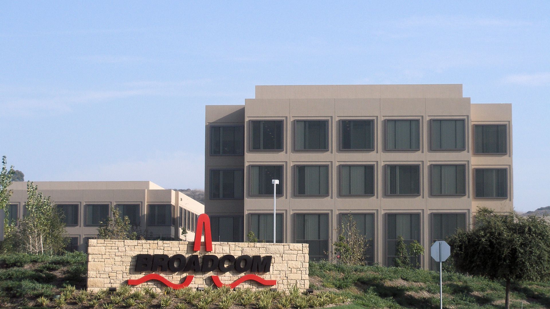 Archival November 2007 photograph of Broadcom's former headquarters in Irvine, California: beige office buildings, dark rectangular windows and a stone Broadcom sign.