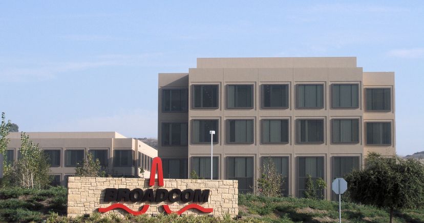 Archival November 2007 photograph of Broadcom's former headquarters in Irvine, California: beige office buildings, dark rectangular windows and a stone Broadcom sign.
