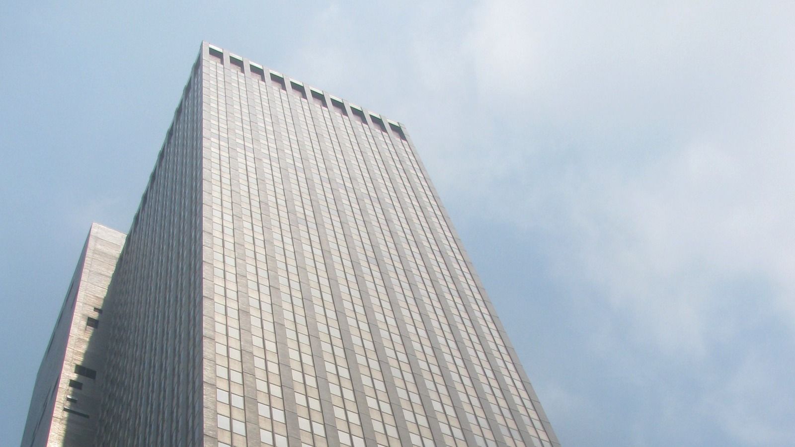 Archival July 2011 low-angle view of the upper facade of 245 Park Avenue in Manhattan, identified by the source as JPMorgan Asset Management, under a cloudy sky.