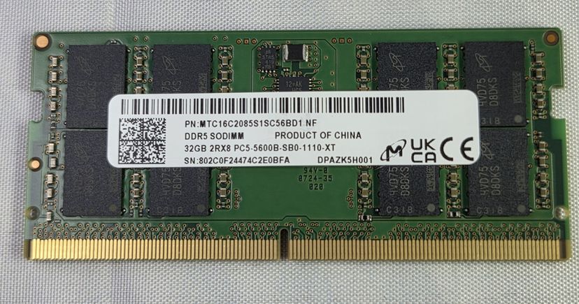 Un module mémoire Micron vert, avec des puces noires et une étiquette blanche, posé sur un tissu.