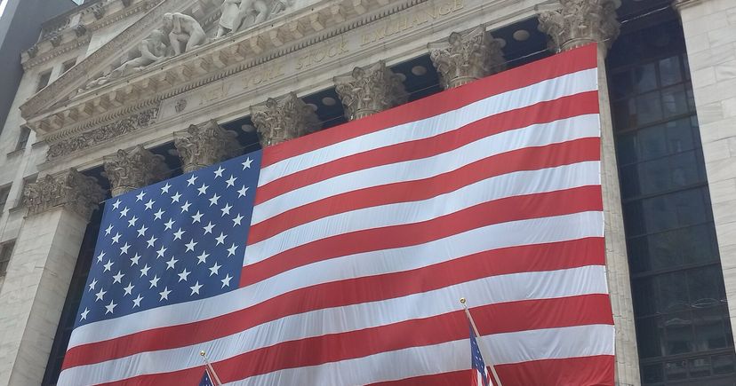 Un grand drapeau américain sur la façade de pierre et les colonnes de la Bourse de New York