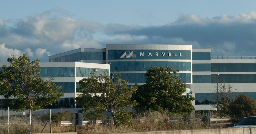 Archival May 2011 photograph of Marvell’s headquarters in Santa Clara, California, showing its white-and-teal facade, Marvell sign, trees and roadside fence.