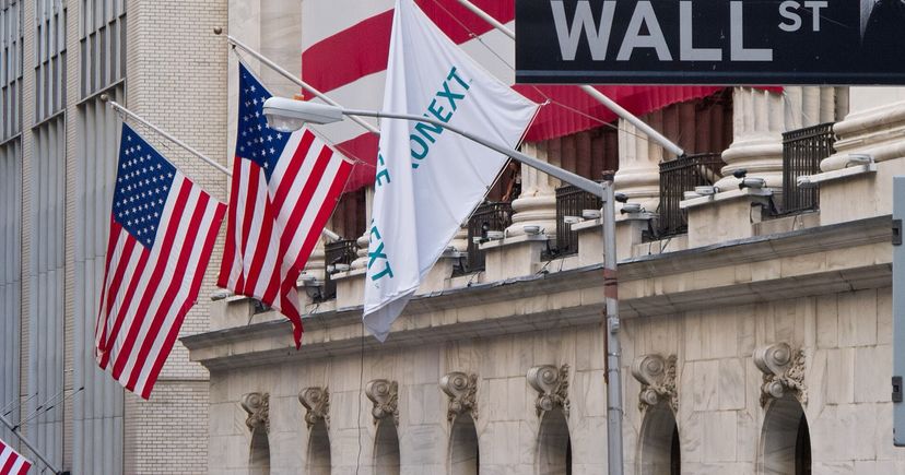 US flags, NYSE facade columns and a Wall Street sign in New York