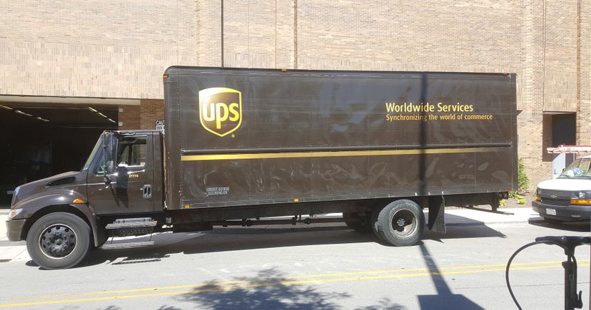 Archival photograph of a brown UPS truck beside a loading dock at Woodfield Mall in Schaumburg, Illinois.