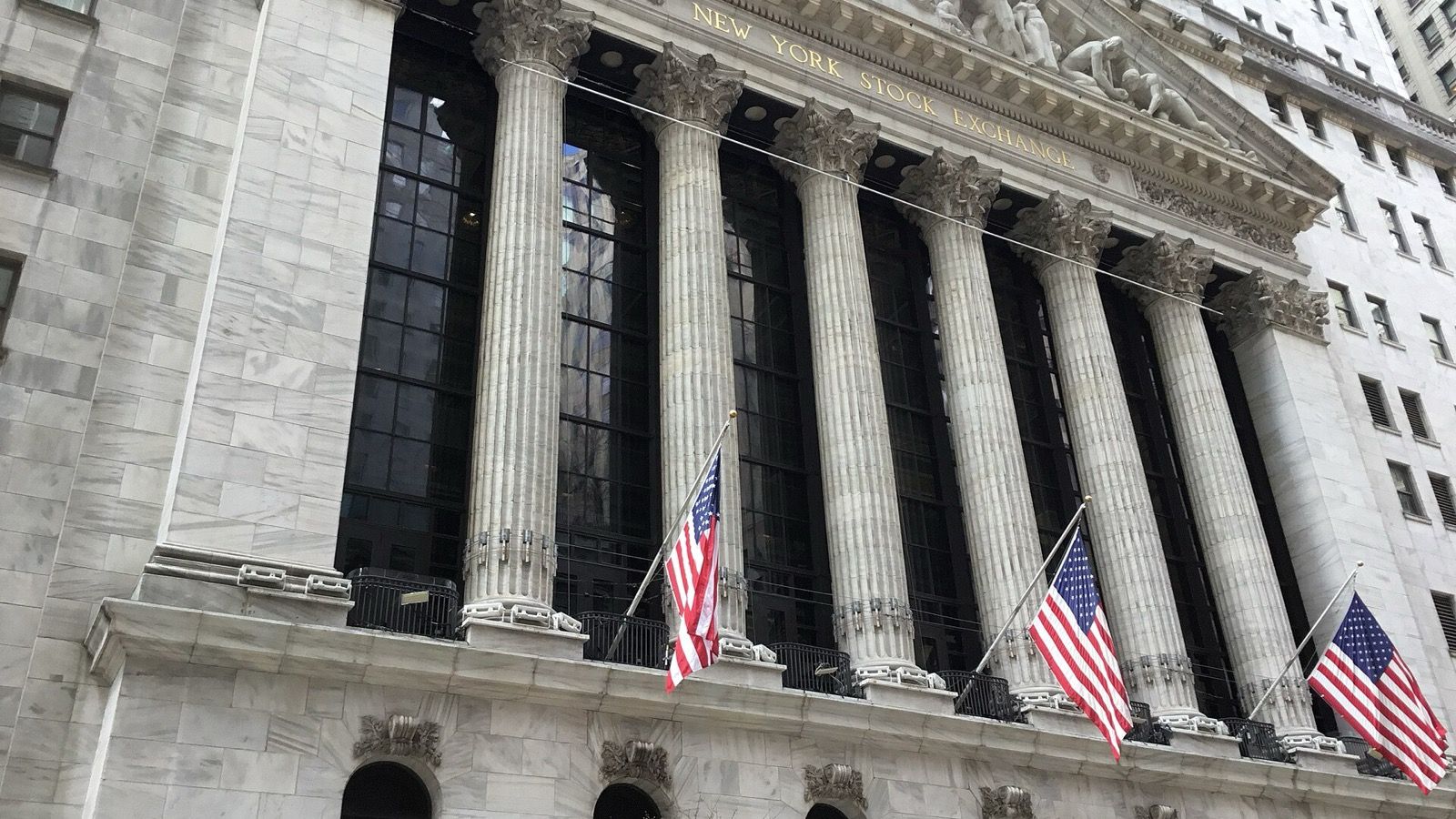 Photo d’archives de la façade en pierre de la Bourse de New York, avec ses colonnes et drapeaux américains.