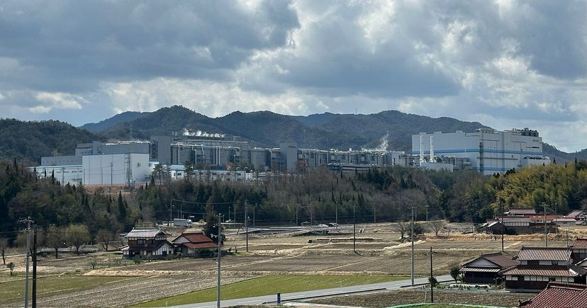 L’usine de puces mémoire de Micron à Higashihiroshima, au Japon, au-delà de champs et au pied de collines boisées