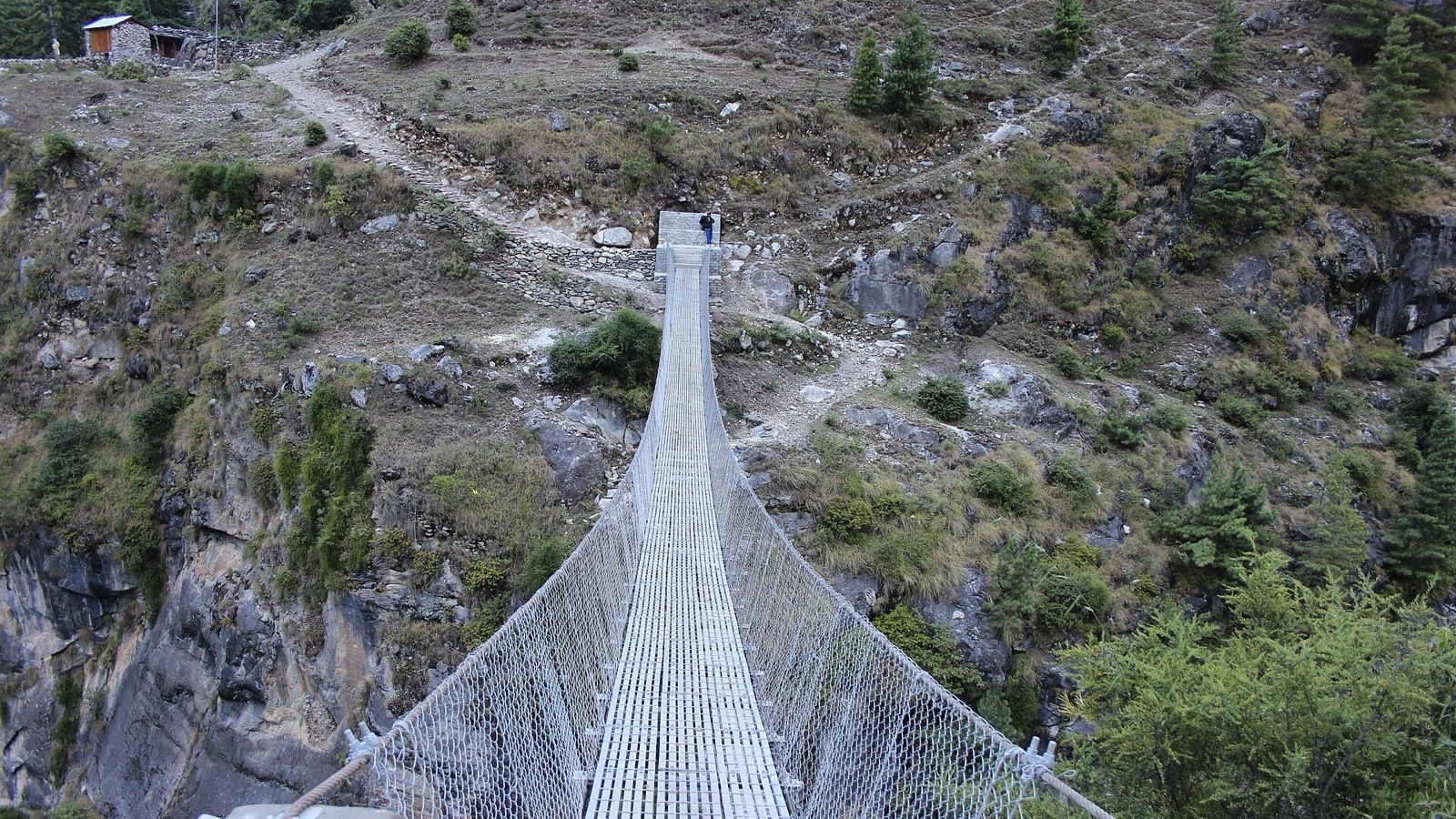 Un étroit pont suspendu pour piétons traverse une gorge rocheuse au Népal.