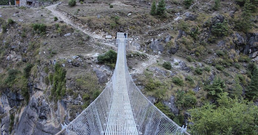 Un étroit pont suspendu pour piétons traverse une gorge rocheuse au Népal.