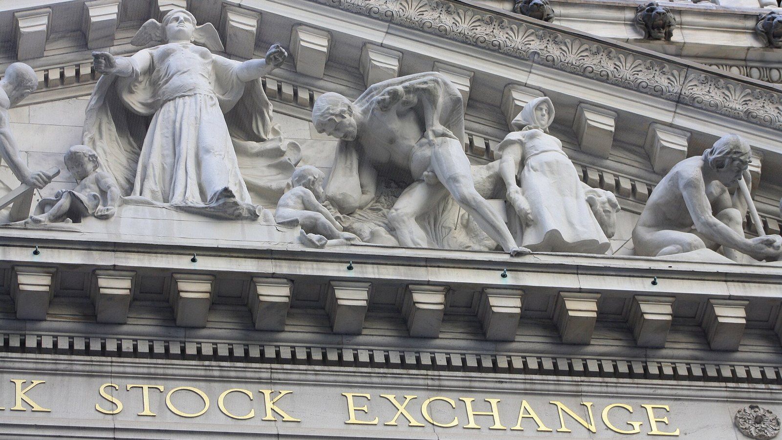Carved stone figures and gold Stock Exchange lettering on the New York Stock Exchange facade.